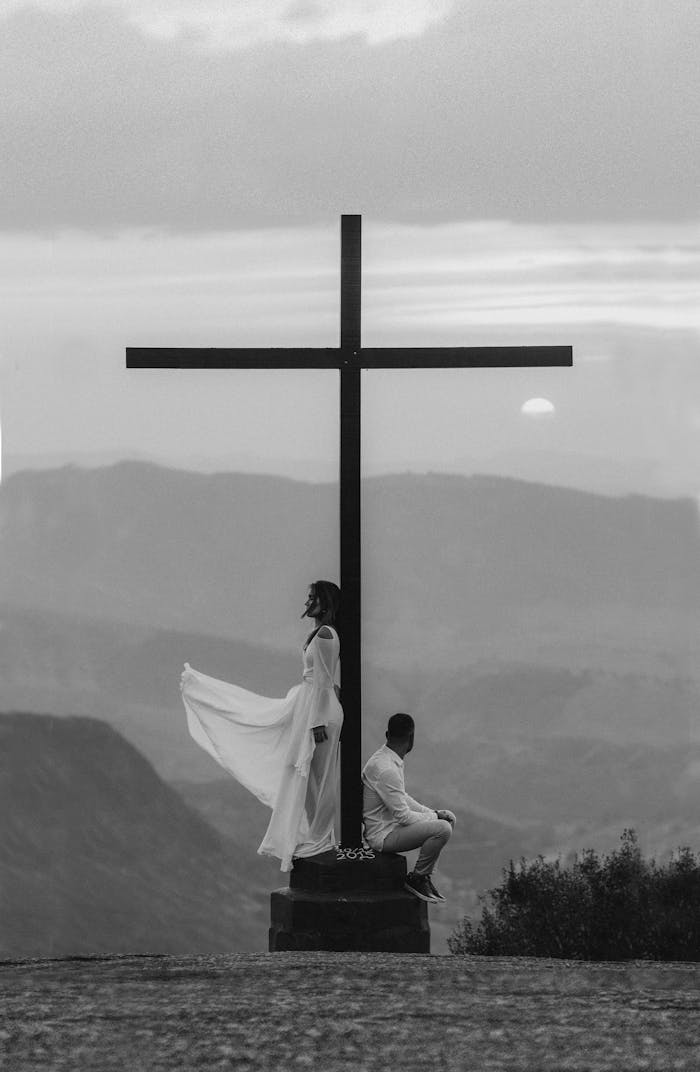 services-02 A serene moment of spiritual reflection by a cross at sunset with a dramatic sky in the background.